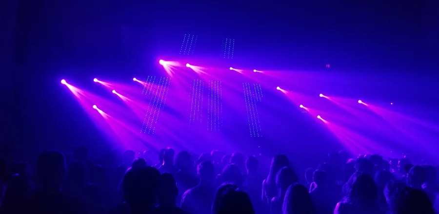 Purple laser beams sweeping over an audience