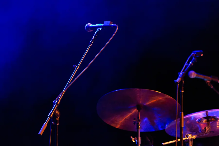Microphones and drums on a stage under blue light