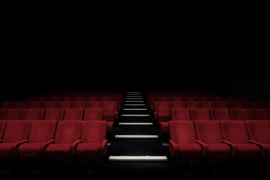 Rows of red theatre seats along a lit aisle